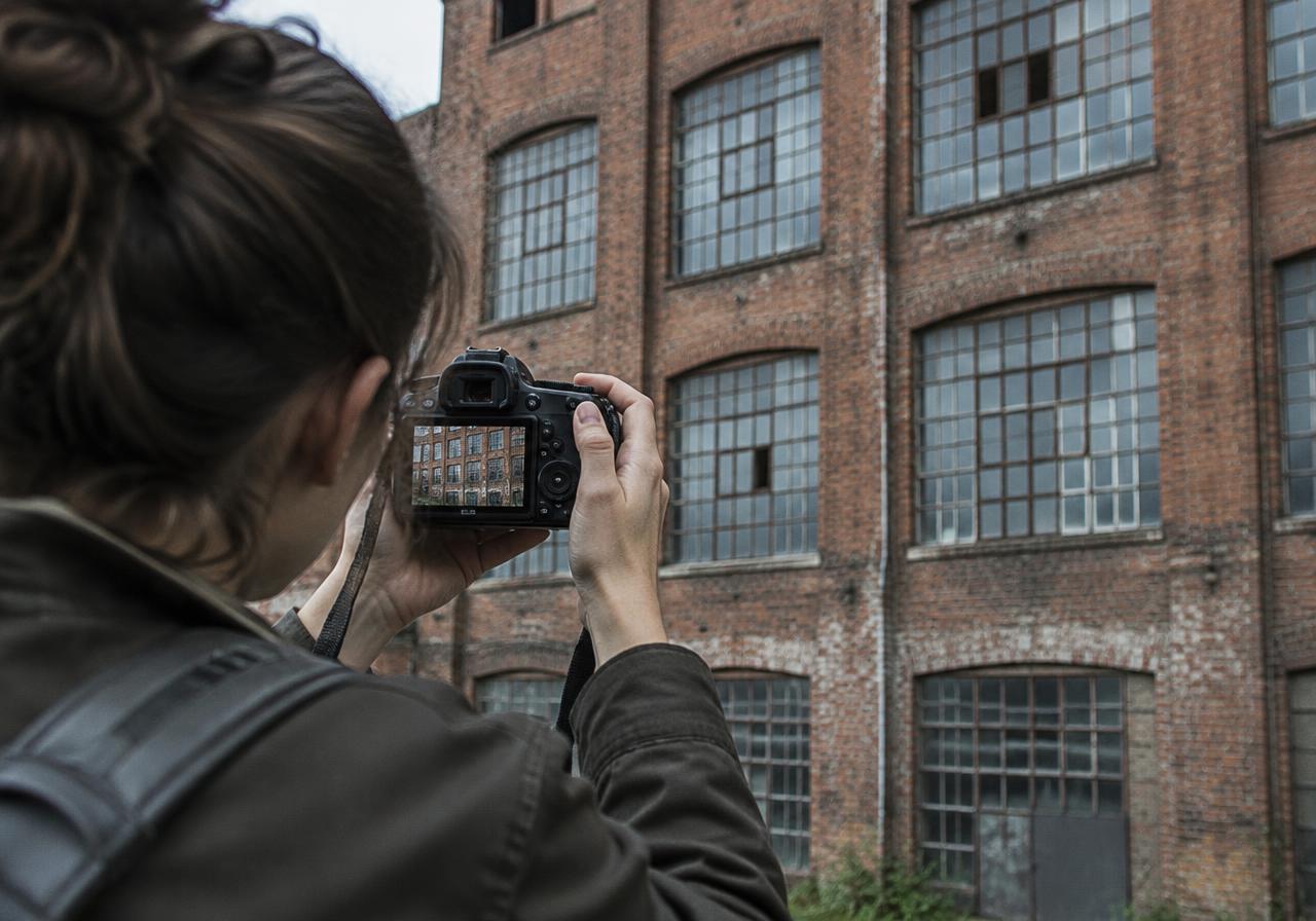 Illustrative image: photographer framing a brick factory facade with a camera